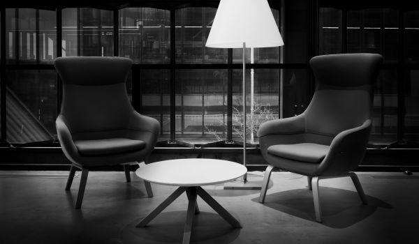 Two armchairs facing each other across a low table, with a lamp in the corner.