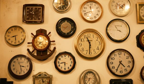 A wall crowded with dozens of different clocks, each showing a different time.
