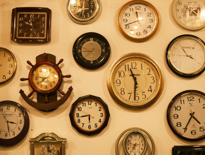A wall crowded with dozens of different clocks, each showing a different time.