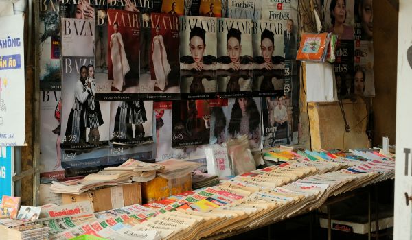 Magazines and newspapers laid out side by side on an outdoor news stall.
