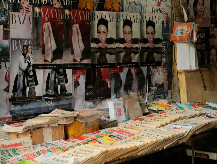 Magazines and newspapers laid out side by side on an outdoor news stall.